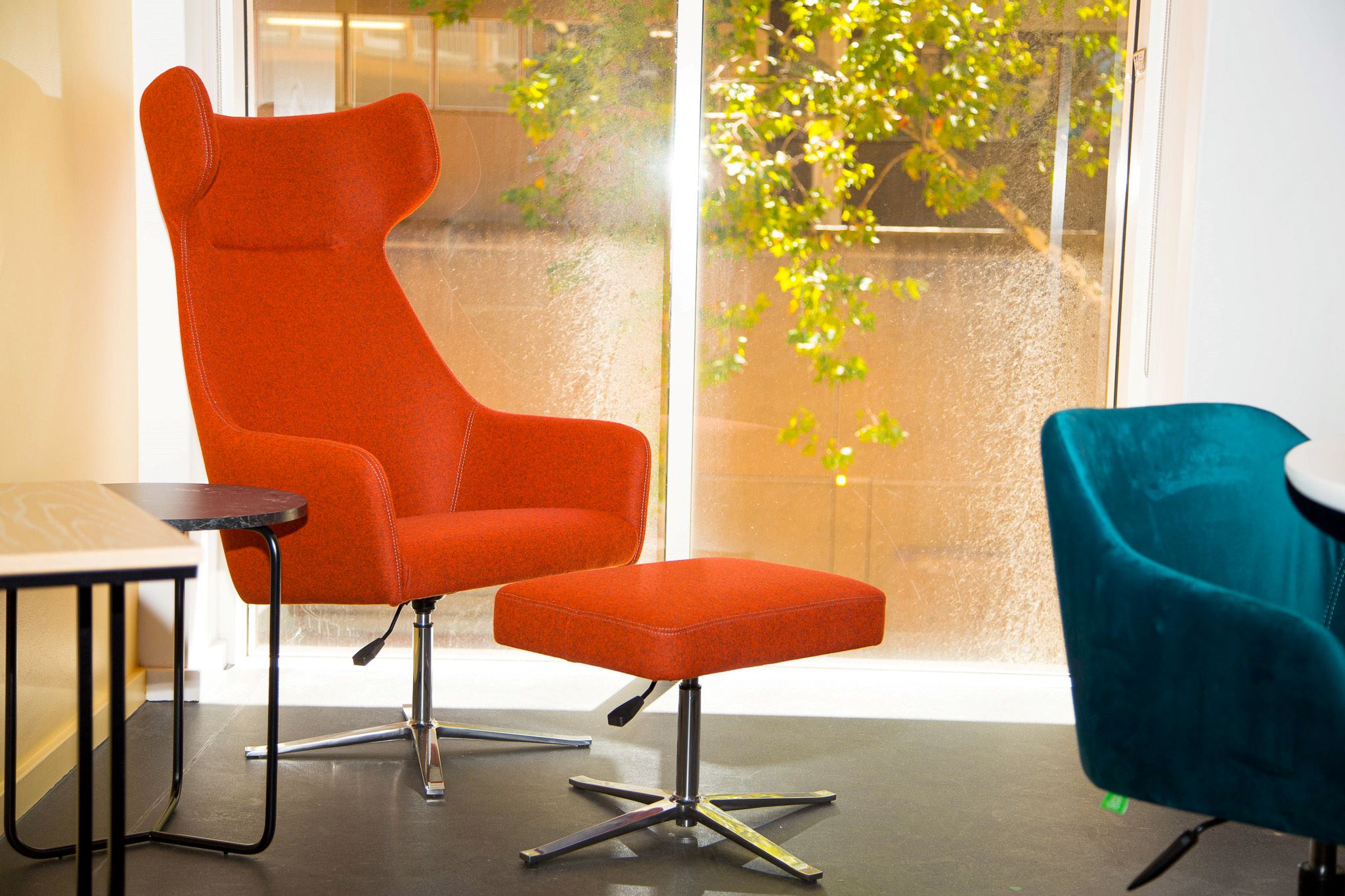 Orange chair and foot rest with side table located in the corner of the Research Commons, Chris Hani Building