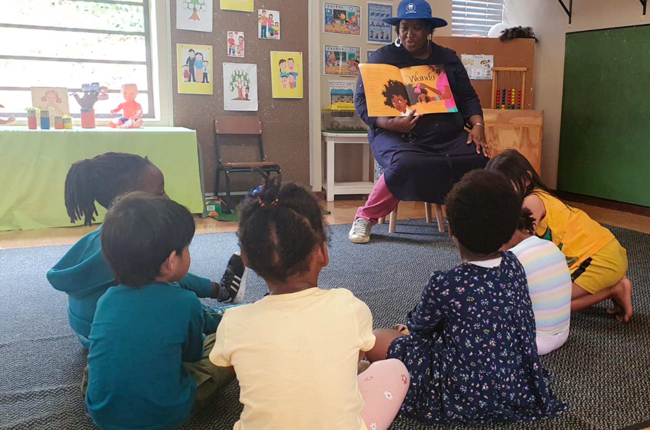 Librarian reads to children seated on carpet floor in classroom