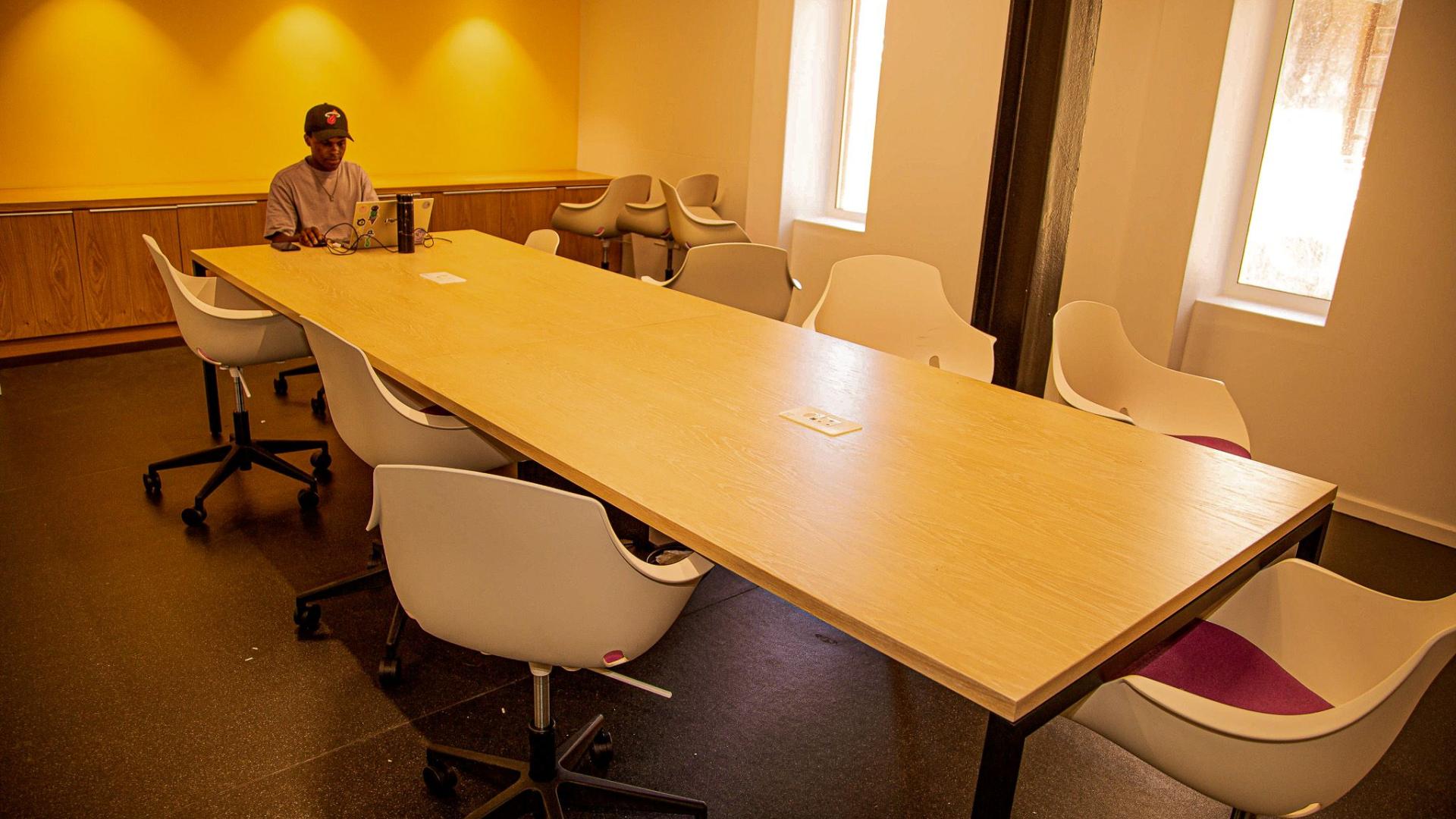 Student on laptop seated front of the long table in the training room, LLL @ Chris Hani