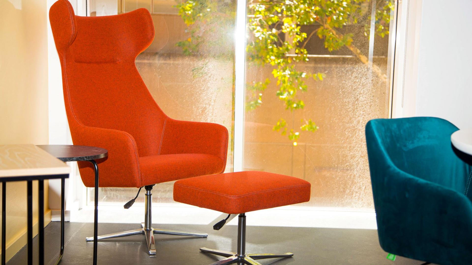 Orange chair and foot rest with side table located in the corner of the Research Commons, Chris Hani Building