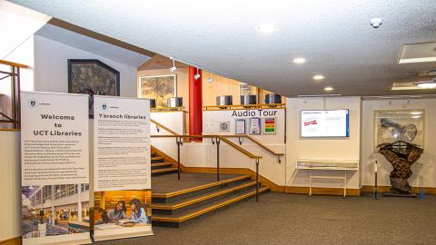 View of Main Library Foyer displaying rollup banners, TV and stairs leading up to the Hub
