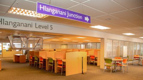 View of Hlanganani study area. Partitioned study desks with green and orange seats