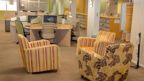 Three comfy chairs and cluster of computer workstations in the background