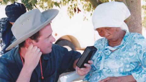 Nigel Crawhall holds up a recorder to record an interview with Ouma Elsie Vaalbooi. Elsie Vaalbooi was a fluent Nǀuu speaker
