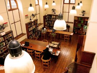 Top view of the Drama Room inside Hiddingh Hall Library. Students seated at long desks with ovehead lighting.