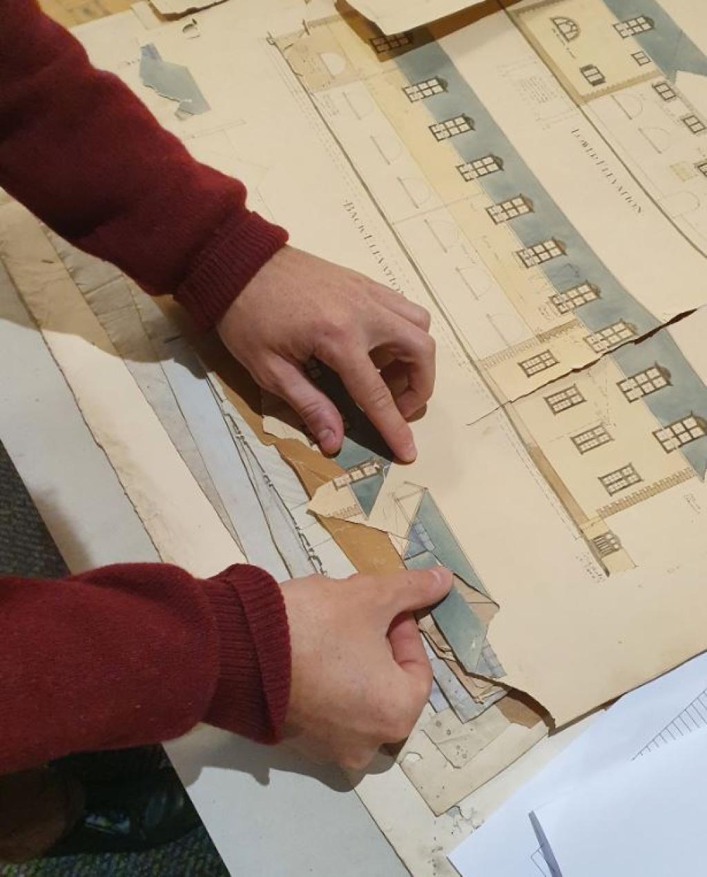 Conservator carefully repairing architectural drawings by hand